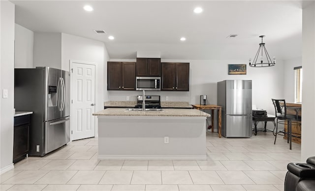 kitchen with stainless steel appliances, a notable chandelier, hanging light fixtures, sink, and an island with sink