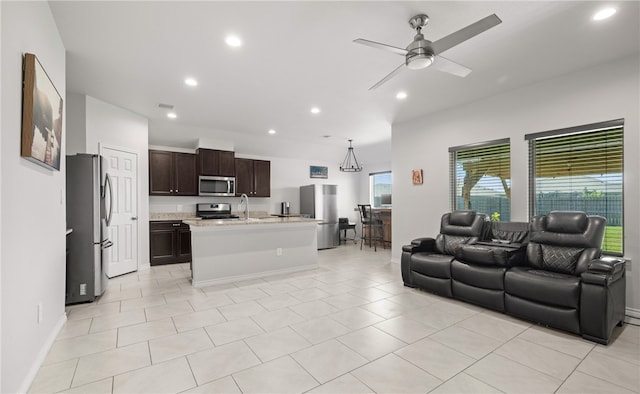 kitchen featuring a wealth of natural light, pendant lighting, appliances with stainless steel finishes, and an island with sink