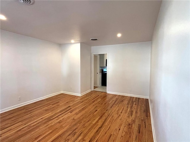 spare room featuring recessed lighting, visible vents, baseboards, and wood finished floors