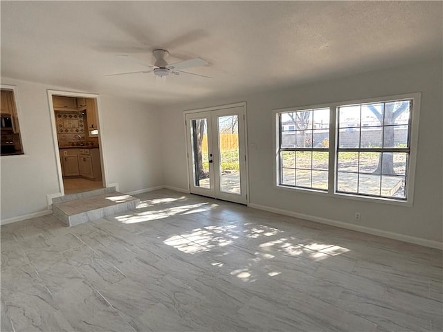 spare room with marble finish floor, french doors, a ceiling fan, and baseboards