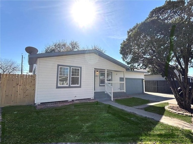 view of front facade with covered porch, driveway, a front lawn, and fence