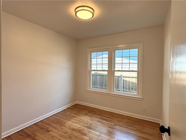 unfurnished room with baseboards and wood finished floors