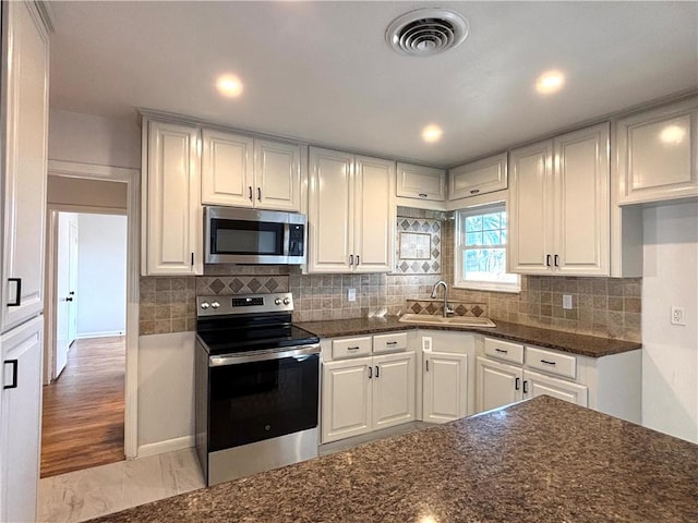 kitchen featuring visible vents, appliances with stainless steel finishes, backsplash, and a sink