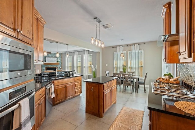 3013 Neches Dr, Corpus Christi, TX 78414 - kitchen featuring appliances with stainless steel finishes, brown cabinetry, a sink, hanging light fixtures, and tasteful backsplash