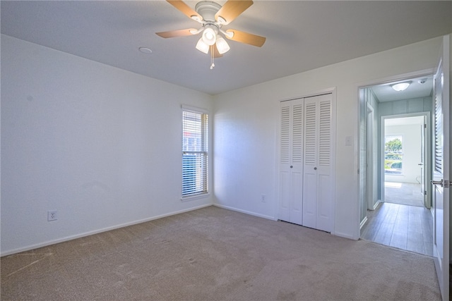 unfurnished bedroom with ceiling fan, light carpet, and a closet