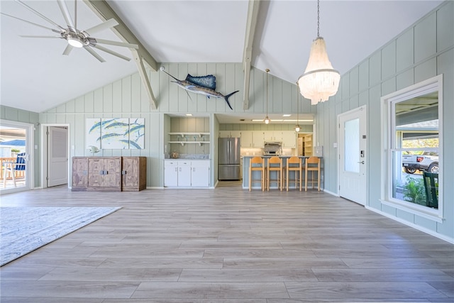 unfurnished living room with ceiling fan, beamed ceiling, high vaulted ceiling, and light wood-type flooring