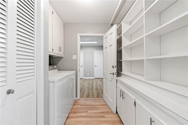 kitchen featuring appliances with stainless steel finishes, sink, white cabinets, light hardwood / wood-style floors, and hanging light fixtures