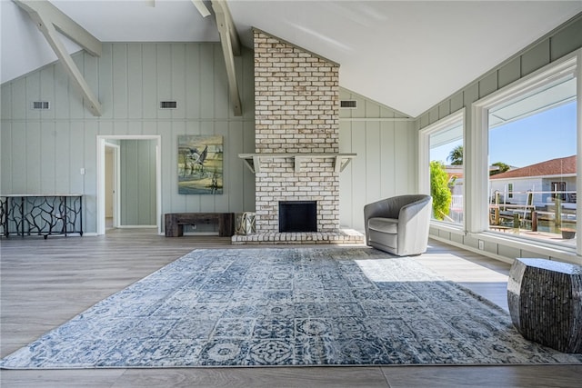 living room featuring hardwood / wood-style floors, lofted ceiling with beams, and a brick fireplace