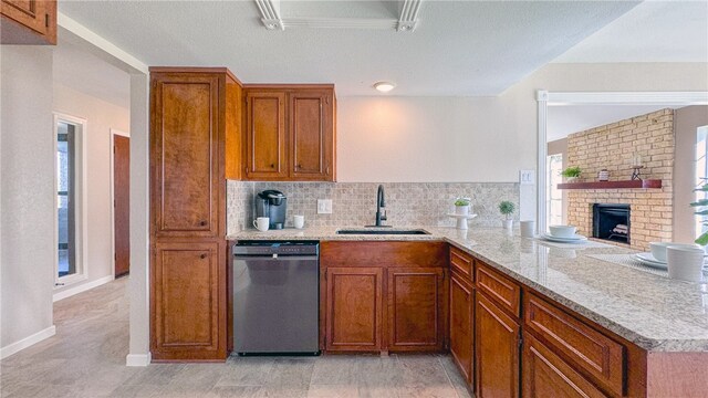 kitchen with a fireplace, sink, backsplash, stainless steel dishwasher, and kitchen peninsula