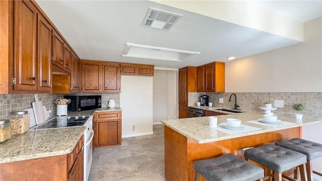 kitchen with a kitchen breakfast bar, kitchen peninsula, sink, and black appliances