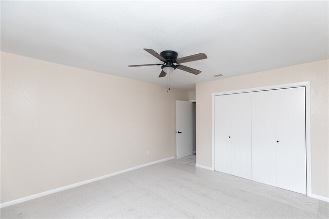 unfurnished bedroom with light colored carpet, ceiling fan, and a closet