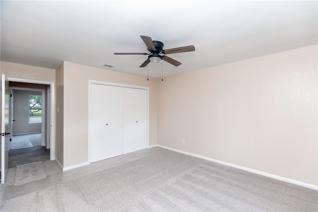 unfurnished bedroom with ceiling fan, light carpet, and a closet