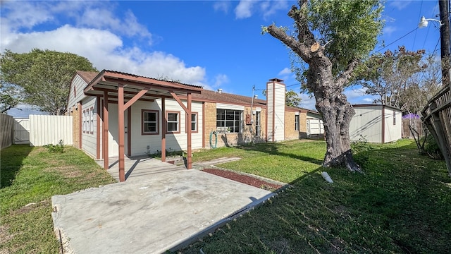 back of property with a shed, a patio area, and a lawn