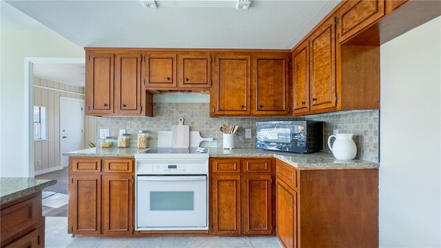 kitchen featuring stove, light stone counters, tasteful backsplash, and light hardwood / wood-style flooring