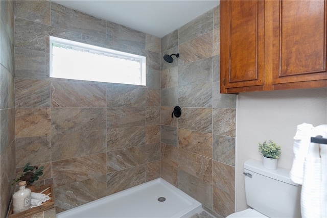 bathroom with a tile shower and toilet