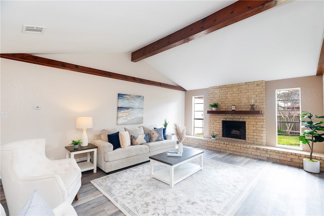 living room featuring lofted ceiling with beams, hardwood / wood-style floors, and a fireplace