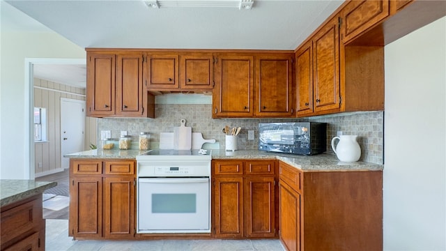 kitchen featuring light stone counters, backsplash, light hardwood / wood-style flooring, and range