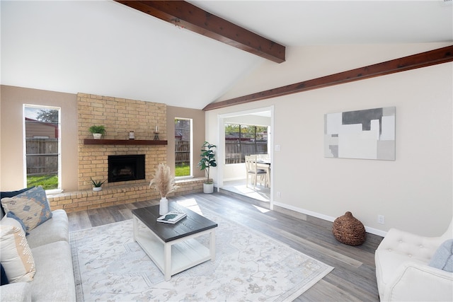 living room featuring wood-type flooring, lofted ceiling with beams, and a brick fireplace