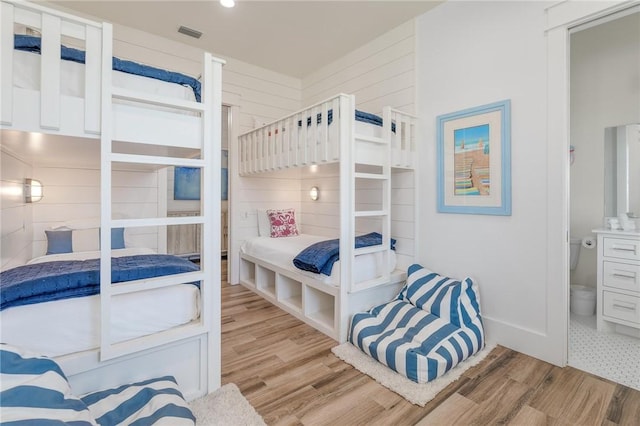 bedroom with light hardwood / wood-style flooring and wooden walls