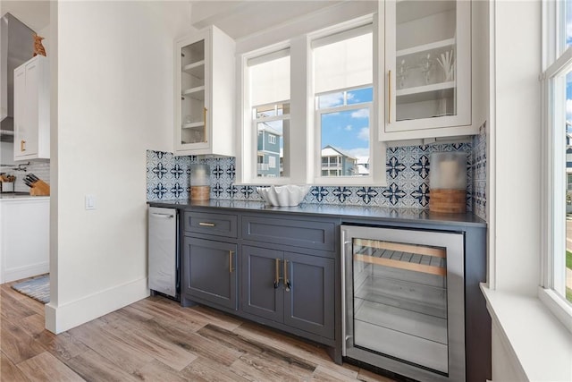 bar with gray cabinetry, white cabinets, light hardwood / wood-style flooring, tasteful backsplash, and beverage cooler