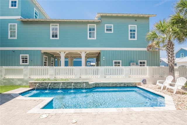 back of property featuring pool water feature and a fenced in pool