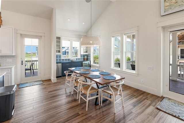 dining area featuring beverage cooler, light wood-type flooring, and high vaulted ceiling