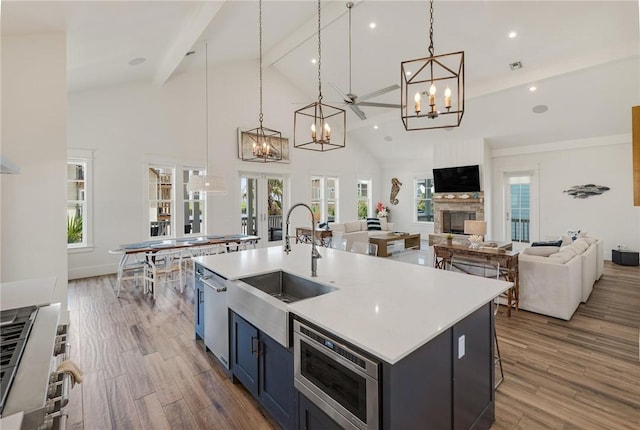 kitchen with a kitchen island with sink, sink, pendant lighting, hardwood / wood-style flooring, and beamed ceiling