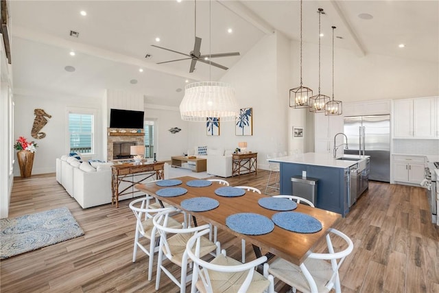 dining space with beamed ceiling, ceiling fan, light hardwood / wood-style floors, and sink