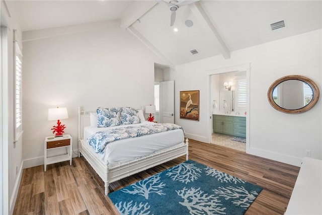 bedroom with ensuite bath, ceiling fan, lofted ceiling with beams, multiple windows, and hardwood / wood-style flooring