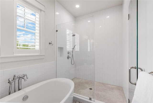 bathroom with shower with separate bathtub and tile walls