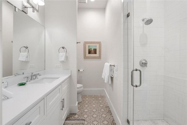 bathroom featuring tile patterned floors, vanity, a shower with shower door, and toilet