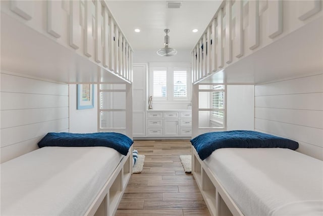 bedroom featuring wooden walls and light hardwood / wood-style flooring