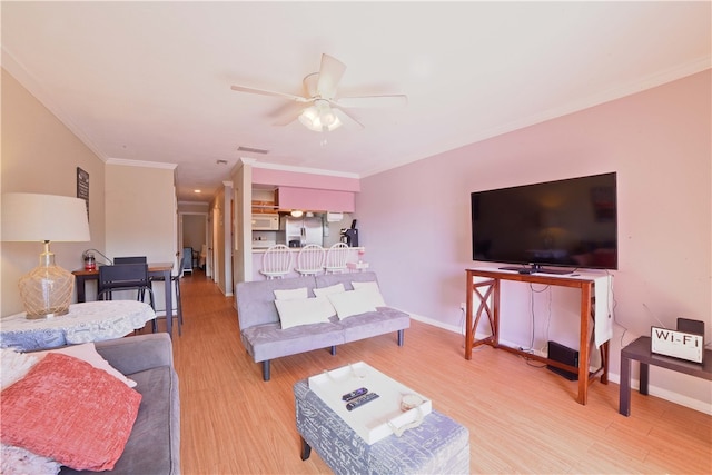 living room featuring ornamental molding, light hardwood / wood-style flooring, and ceiling fan