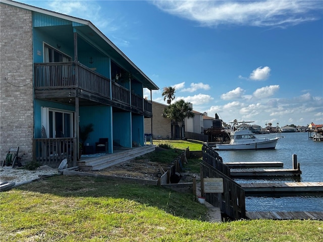 view of dock featuring a balcony, a yard, and a water view