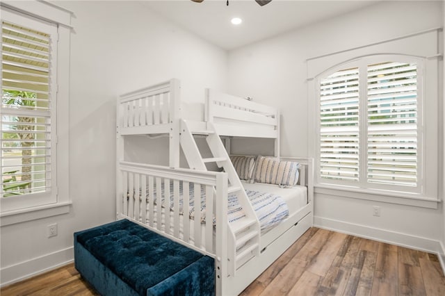 bedroom with multiple windows, baseboards, and wood finished floors