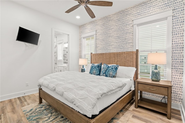 bedroom featuring baseboards, a ceiling fan, ensuite bath, light wood-style flooring, and recessed lighting