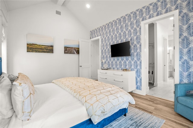 bedroom featuring lofted ceiling, wallpapered walls, light wood-type flooring, and visible vents