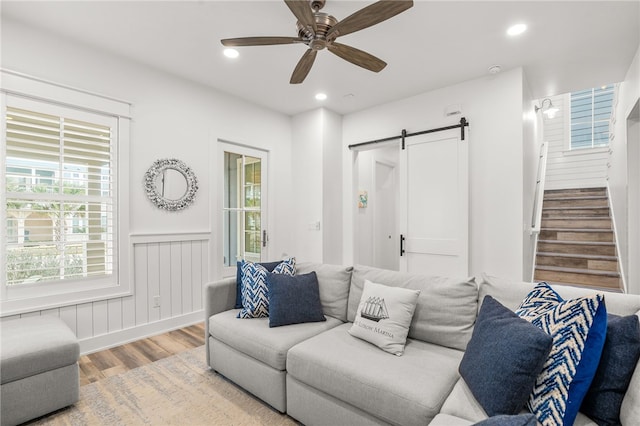 living room featuring stairs, a barn door, wood finished floors, and recessed lighting