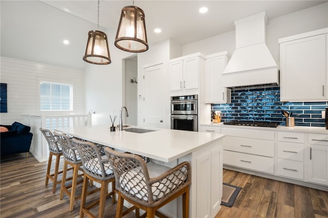 kitchen featuring black gas stovetop, an island with sink, a sink, and custom range hood