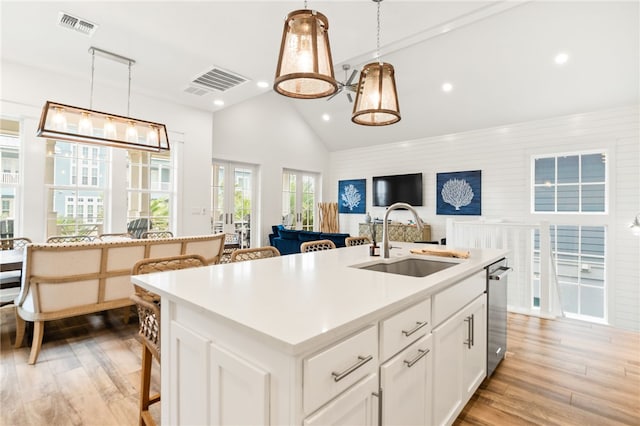 kitchen featuring open floor plan, white cabinetry, a sink, and a center island with sink