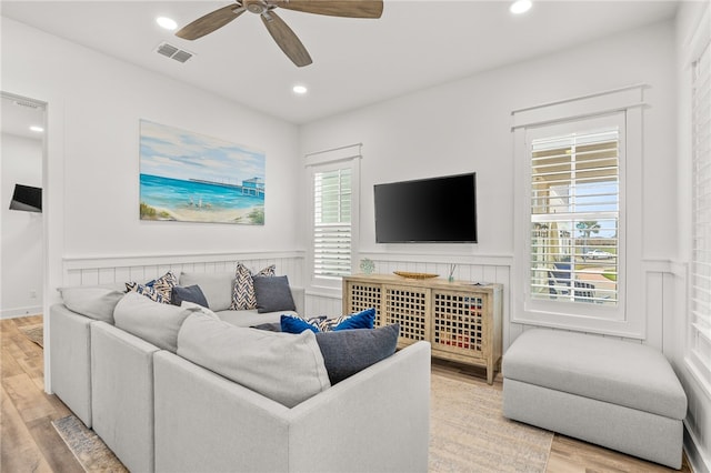 living room featuring wainscoting, wood finished floors, visible vents, and a healthy amount of sunlight