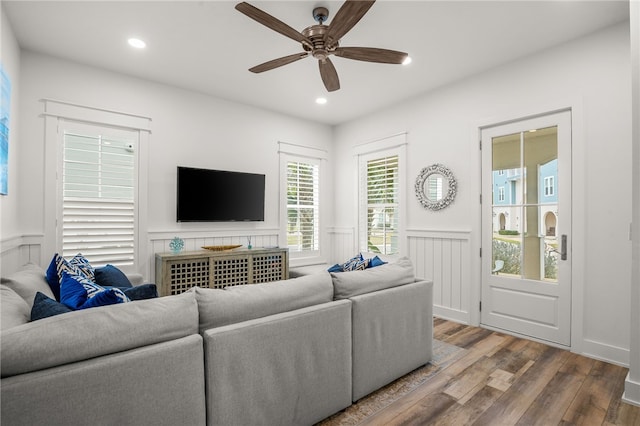 living area with a ceiling fan, recessed lighting, a wainscoted wall, and wood finished floors