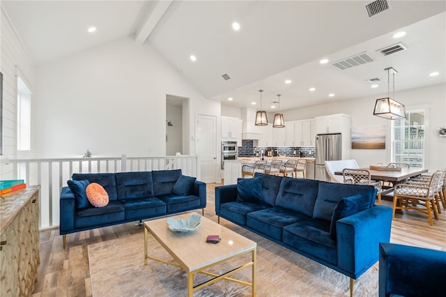 living area featuring light wood-type flooring, visible vents, and beam ceiling