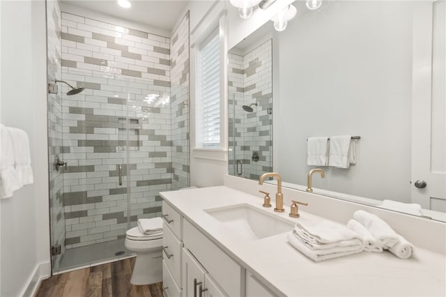 full bathroom with a stall shower, vanity, toilet, and wood finished floors