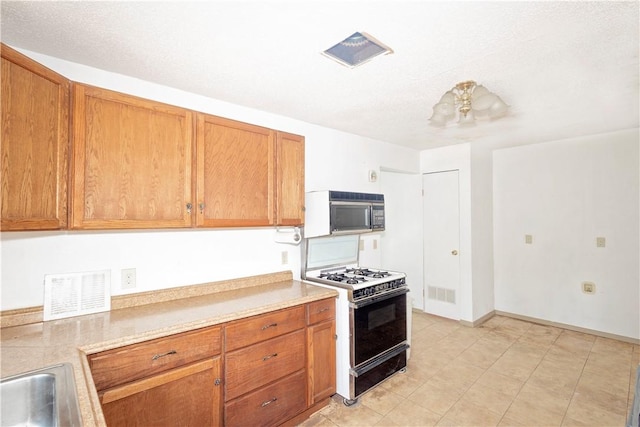 2407 David St, Corpus Christi, TX 78405 - kitchen with white range with gas cooktop, brown cabinets, light countertops, and light tile patterned floors