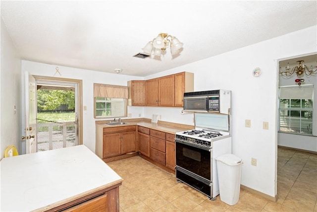 2407 David St, Corpus Christi, TX 78405 - kitchen with black microwave, white gas range, light countertops, brown cabinets, and light tile patterned floors