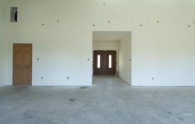 empty room featuring a towering ceiling and unfinished concrete floors