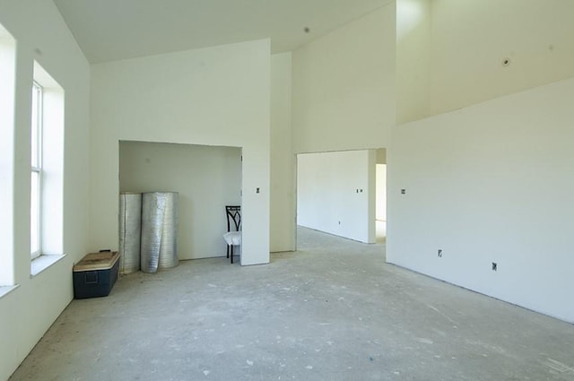 unfurnished living room featuring a towering ceiling