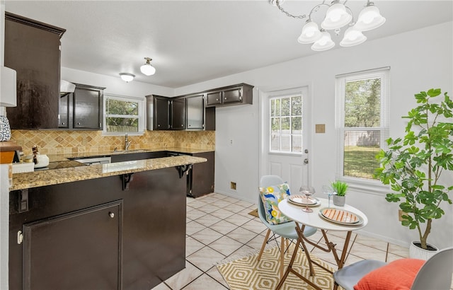 102 Mallard Dr, Aransas Pass, TX 78336 - kitchen featuring decorative backsplash, a chandelier, a sink, dark brown cabinetry, and a peninsula