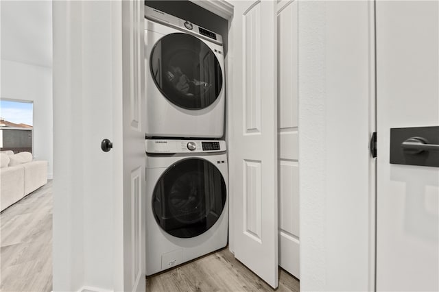 laundry room with light hardwood / wood-style floors and stacked washer / drying machine